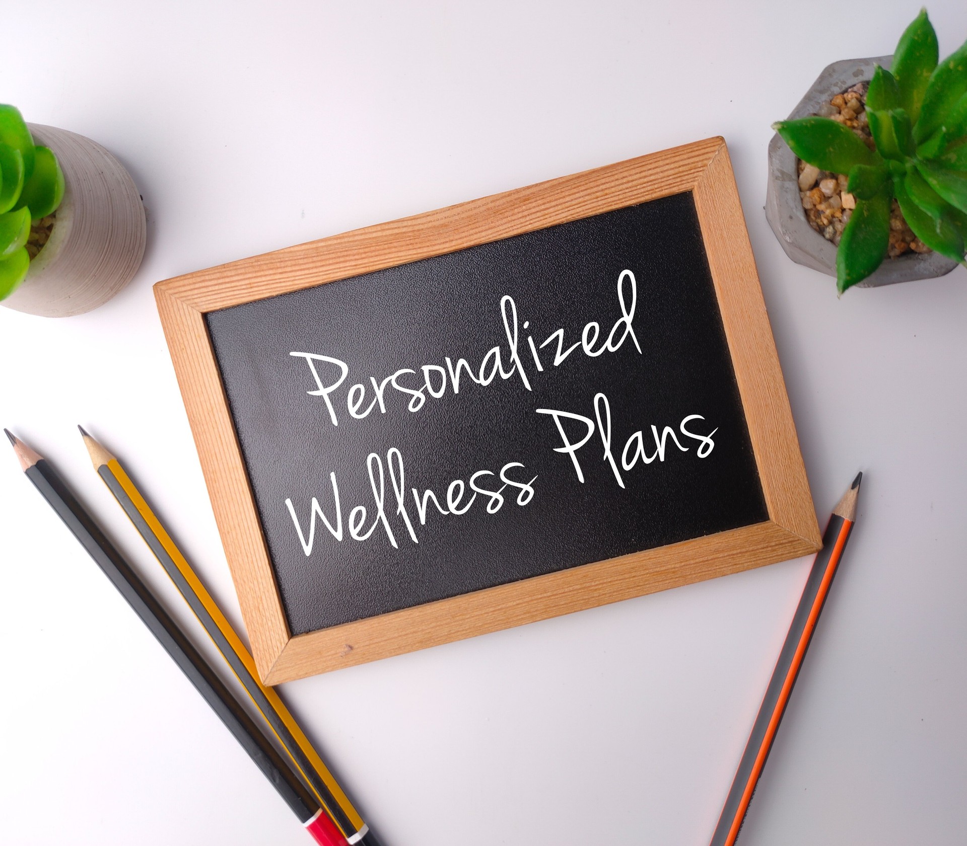 Top view wooden board and green plant with the word Personalized Wellness Plans on a white background